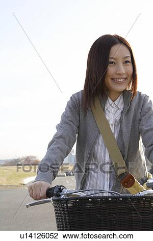 Stock Image - Close-up of young woman on a bicycle. Fotosearch