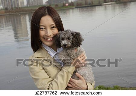 Portrait of a young woman holding her pet dog View Large Photo Image Stock Image - Portrait of a young woman holding her pet dog. Fotosearch