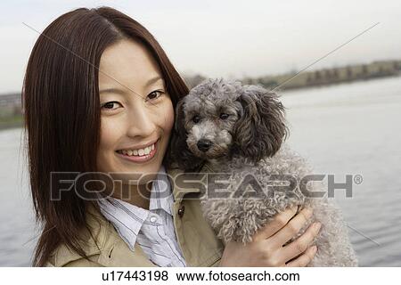Stock Photo - Portrait of a young woman holding her pet dog. Fotosearch