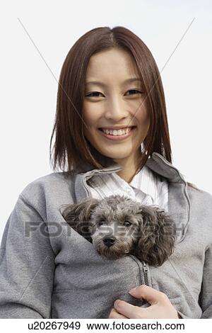Portrait of a young woman holding her pet dog inside her jacket View Large Photo Image Stock Photo - Portrait of a young woman holding her pet dog inside her jacket. Fotosearch