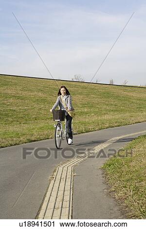 Stock Image - Portrait of a young woman riding a bicycle. Fotosearch