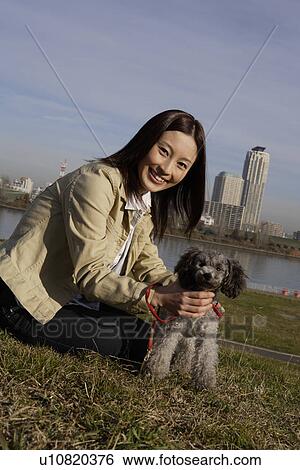Stock Photograph - Portrait of a young woman sitting with her pet dog. Fotosearch