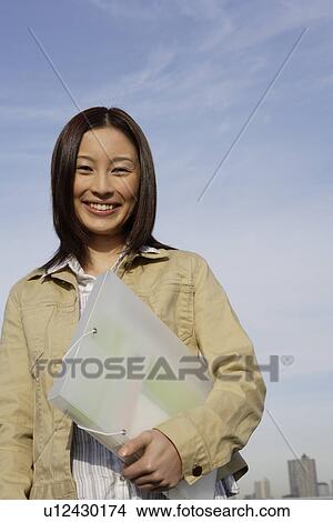 Picture - Portrait of a young woman with a folder in her hand. Fotosearch