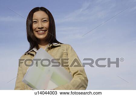 Stock Image - View of a young woman holding a folder. Fotosearch