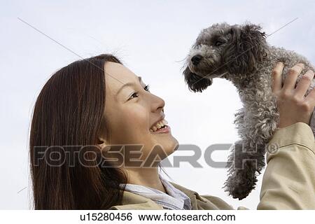 View of a young woman holding her pet dog View Large Photo Image Stock Photograph - View of a young woman holding her pet dog. Fotosearch