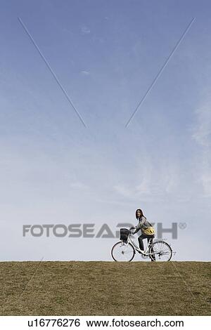 Stock Photograph - View of a young woman riding a bicycle. Fotosearch