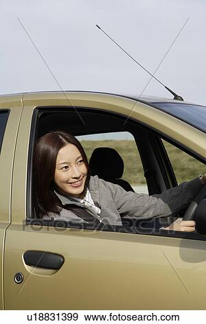Stock Photo - View of a young woman sitting in a car. Fotosearch