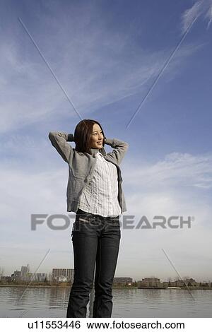 View of a young woman standing near a lake View Large Photo Image Stock Photograph - View of a young woman standing near a lake. Fotosearch