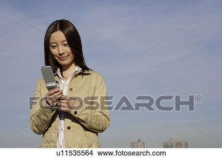 Picture - View of a young woman using cellphone. Fotosearch