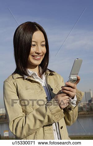 Stock Image - View of a young woman using cellphone. Fotosearch
