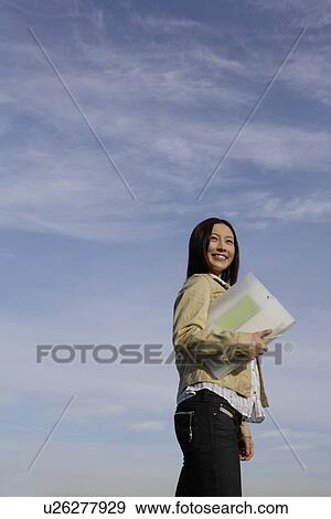 View of a young woman with a folder in her hand View Large Photo Image Stock Photo - View of a young woman with a folder in her hand. Fotosearch