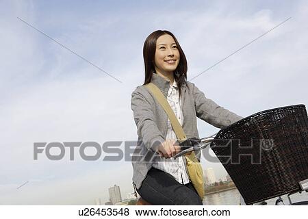Stock Photo - View of young woman riding a bicycle. Fotosearch