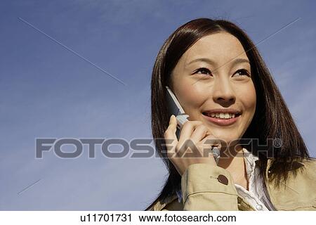 Stock Image - View of young woman using cellphone. Fotosearch