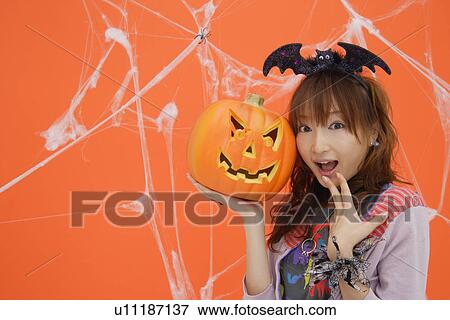 Close-up of teenage girl holding jack-o-lantern View Large Photo Image Stock Photo - Close-up of teenage girl holding jack-o-lantern. Fotosearch