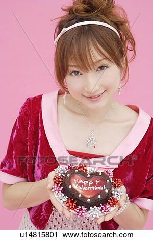Stock Image - Portrait of a teenage girl holding a cake. Fotosearch