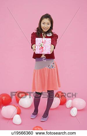 Stock Image - Portrait of a teenage girl holding a gift box. Fotosearch