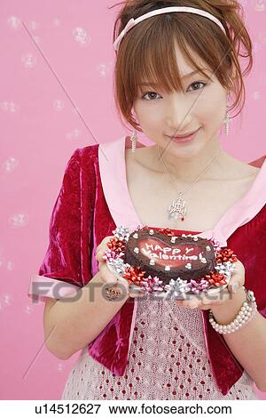 Stock Photo - Portrait of a teenage girl holding a cake. Fotosearch