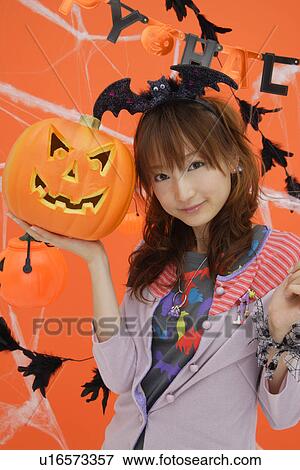 Stock Photo - Portrait of teenage girl holding jack-o-lantern. Fotosearch