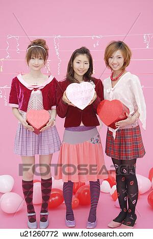 Stock Image - Portrait of teenage girls holding boxes. Fotosearch