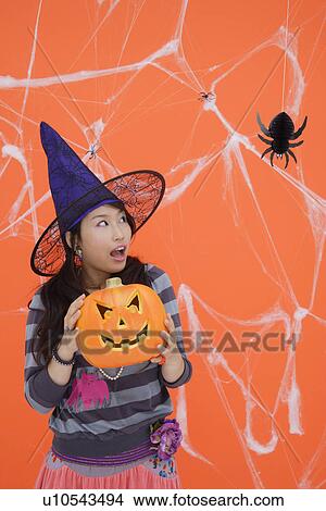 Picture - View of a teenage girl with jack-o-lantern. Fotosearch