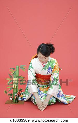 Stock Photo - View of teenage girl in traditional outfit beside a plant. Fotosearch