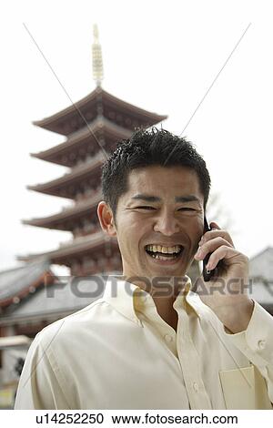Stock Image - A smiling young man using cellphone. Fotosearch