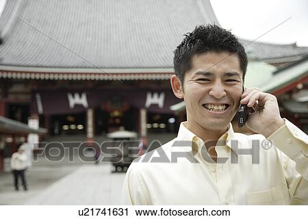 A smiling young man using cellphone View Large Photo Image Stock Image - A smiling young man using cellphone. Fotosearch