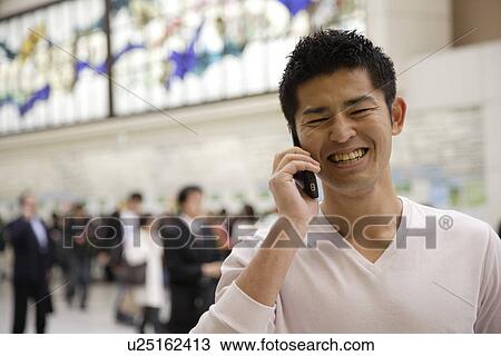 Stock Image - A smiling young man using cellphone. Fotosearch