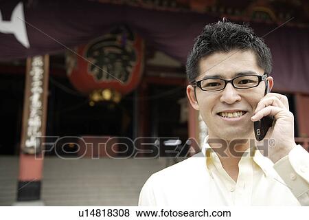 Stock Photo - A smiling young man using cellphone. Fotosearch