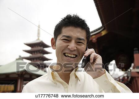 Stock Photo - A smiling young man using cellphone. Fotosearch