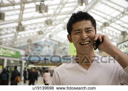 A smiling young man using cellphone View Large Photo Image Stock Photo - A smiling young man using cellphone. Fotosearch