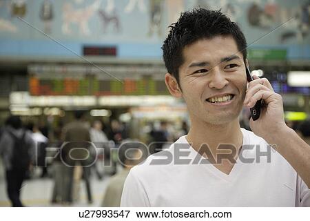 A smiling young man using cellphone View Large Photo Image Stock Photo - A smiling young man using cellphone. Fotosearch
