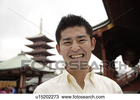 Stock Image - A young man standing outside temple. Fotosearch