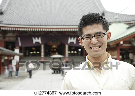 Stock Photo - A young man standing outside temple. Fotosearch