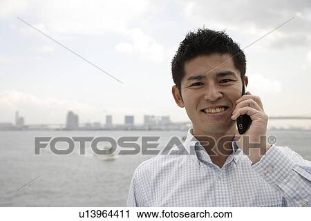 Stock Image - Close-up of a young man using mobile phone. Fotosearch