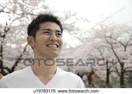 Stock Photo - Close-up of a young man with trees in background. Fotosearch