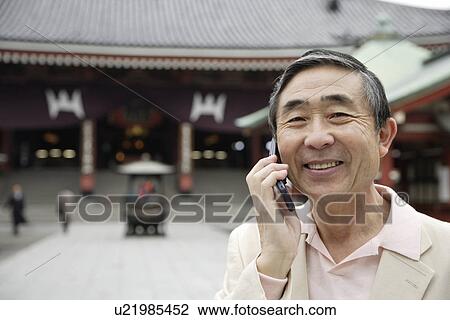Stock Image - Portrait of a smiling senior man using mobile phone. Fotosearch