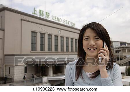 Stock Image - Close-up of a young woman using mobile phone. Fotosearch