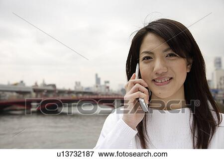 Stock Photo - Close-up of a young woman using mobile phone. Fotosearch