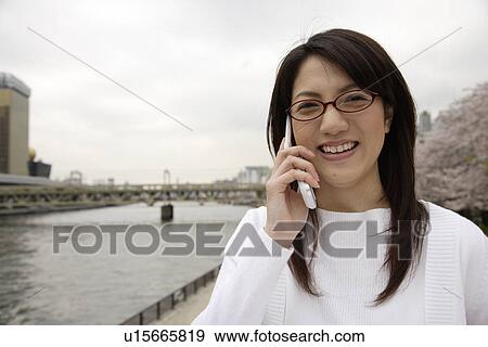 Stock Photo - Close-up of a young woman using mobile phone. Fotosearch