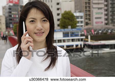 Stock Photo - Close-up of a young woman using mobile phone. Fotosearch