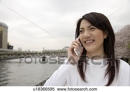 Stock Photography - Close-up of a young woman using mobile phone. Fotosearch