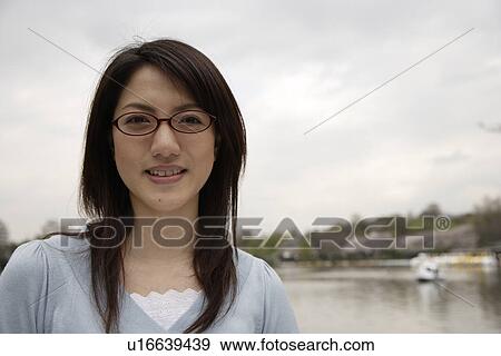 Portrait of a smiling young woman wearing glasses View Large Photo Image Stock Photo - Portrait of a smiling young woman wearing glasses. Fotosearch