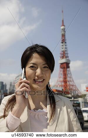 Stock Image - Portrait of a smiling young woman using mobile phone. Fotosearch