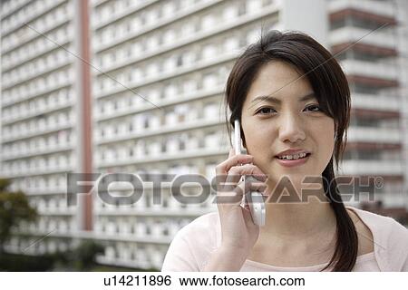 Stock Photograph - Portrait of a young woman using mobile phone. Fotosearch
