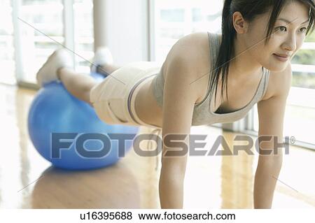 Stock Photo - A woman works out in the gym as she performs the exercise for abs. Fotosearch