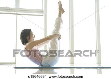 Picture - A young woman is elated as she holds her legs straight up in the air. Fotosearch