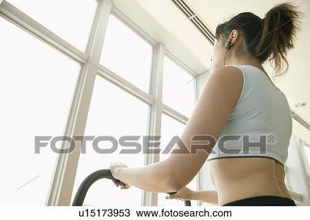 Stock Image - A young woman performs an exercise in a well equipped gym. Fotosearch