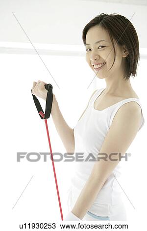 Stock Image - A young woman smiles as she uses the stretching rope for an exercise. Fotosearch