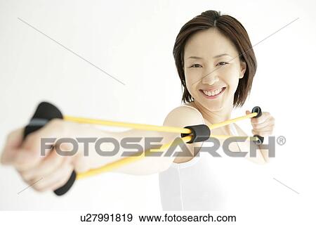 A young woman smiles as she uses the stretching rope for an exercise View Large Photo Image Stock Photo - A young woman smiles as she uses the stretching rope for an exercise. Fotosearch
